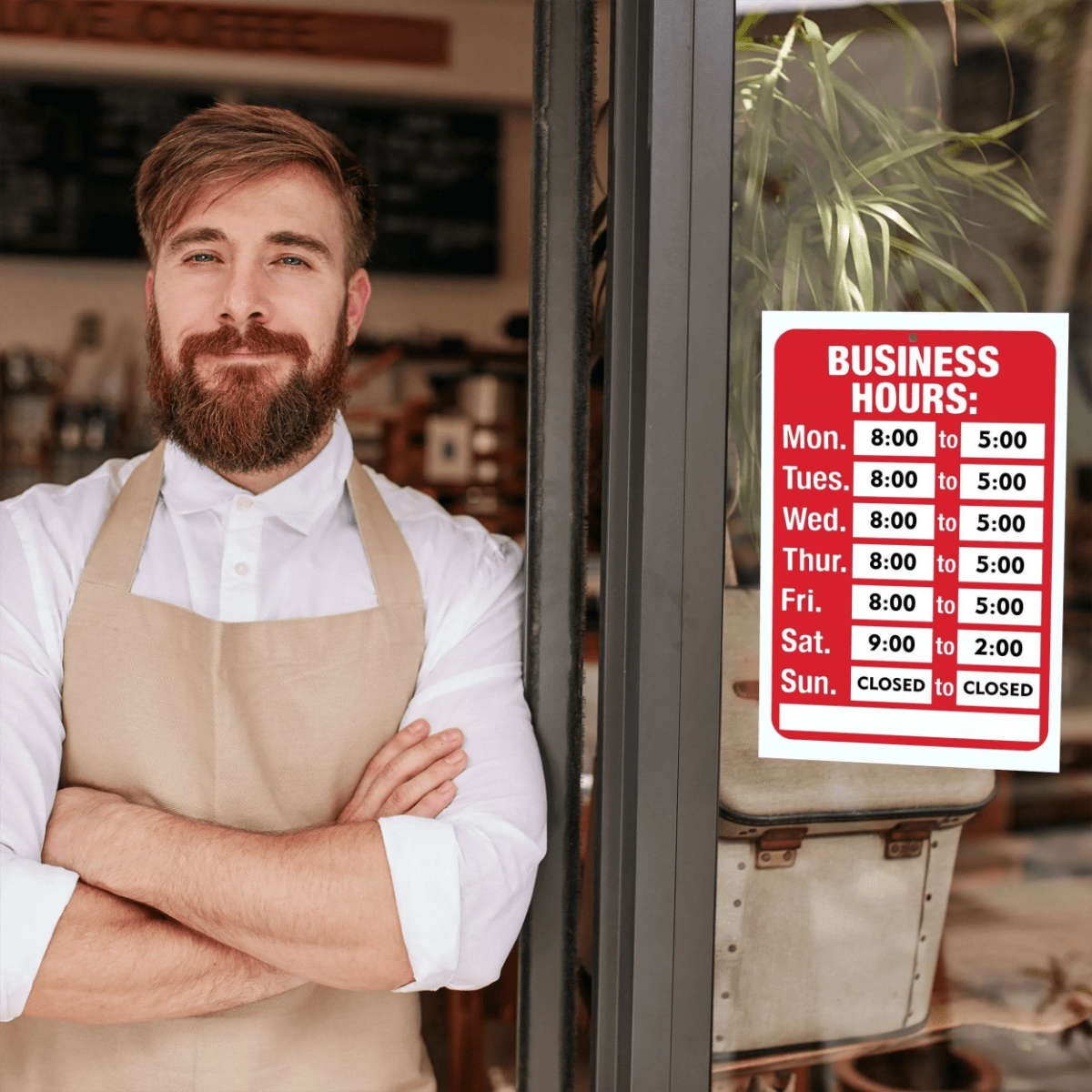 A bearded man leans against a store door next to a business hours window sign that’s been customized with number (time) stickers and closed stickers to designate the business’s opening hours.