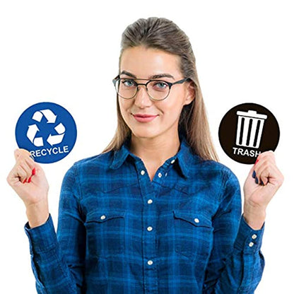 A woman holding a blue recycle sticker in one hand and a black trash sticker in the other, demonstrating the size and design of the stickers