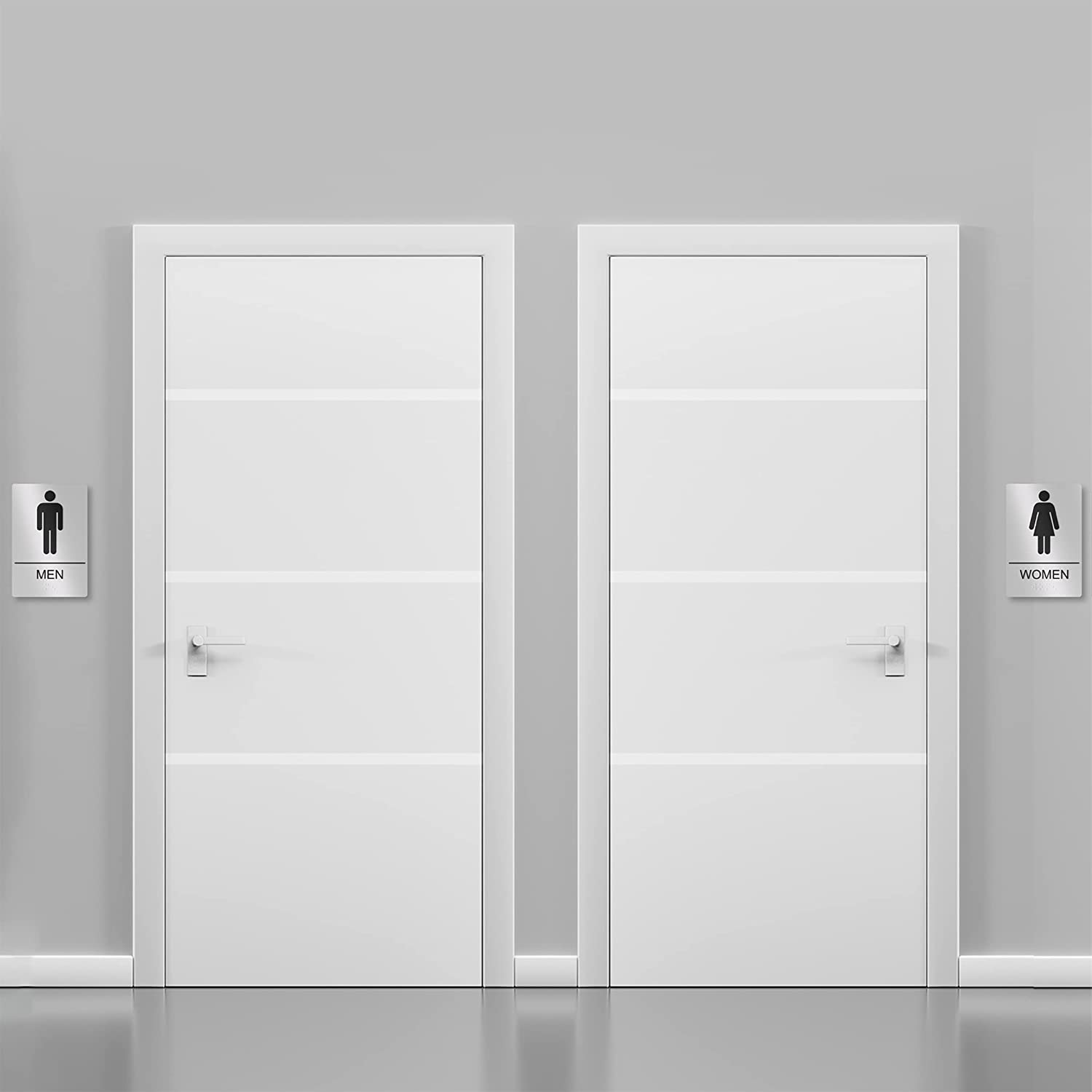 Silver restroom signs installed on doors for men and women, clearly indicating bathroom locations