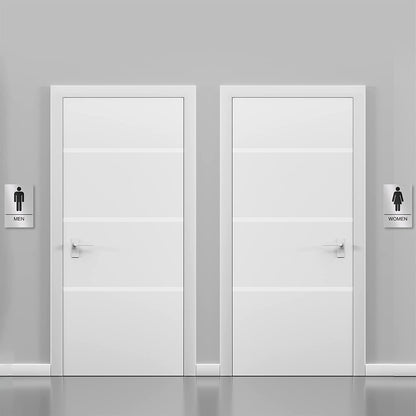 Silver restroom signs installed on doors for men and women, clearly indicating bathroom locations