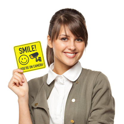 Woman holding a Smile You're On Camera Sticker, showcasing its compact size and bold design for easy application and visibility