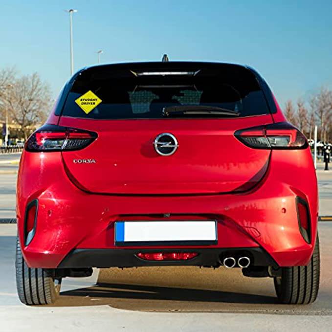 A red car with a student driver sticker on the rear window, demonstrating how the sticker appears when attached to the back of the vehicle